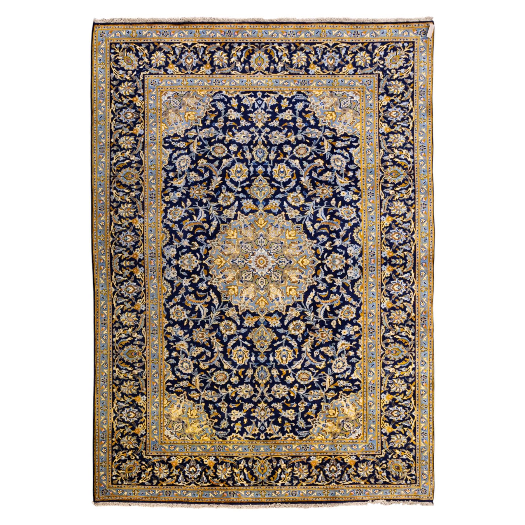 Central Persian Kashan hand-knotted rug, deep indigo field with central floral medallion surrounded by an all-over arrangement of palmettes, flowering vines, and tendrils with matching spandrels enclosed by a pale blue floral main border with multiple narrow guard stripes, with cotton fringe ends 