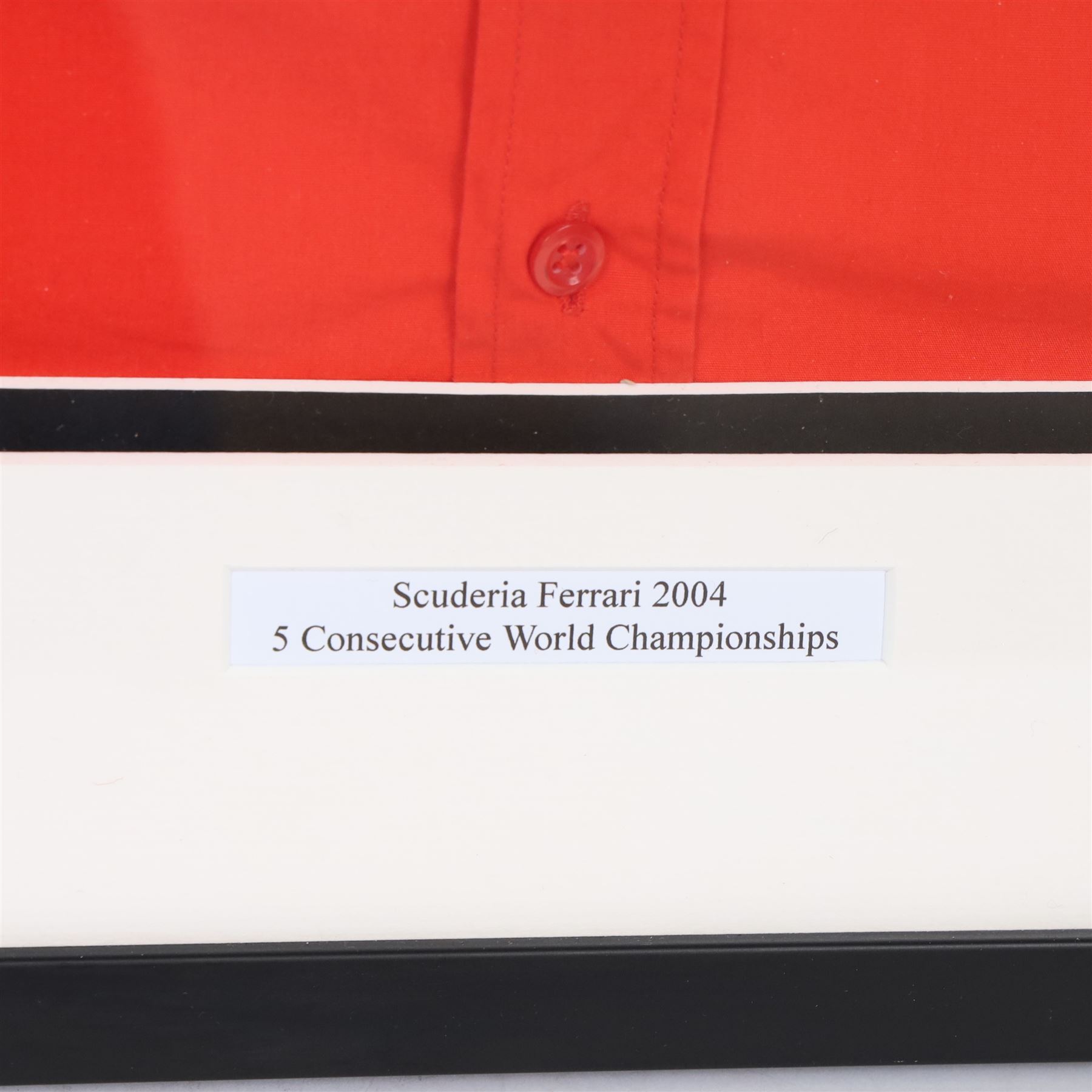 Scuderia Ferrari 2004 shirt, bearing four signatures including Michael Schumacher and Rubens Barrichello, to commemorate five consecutive World Championship wins, in glazed frame, frame H85cm