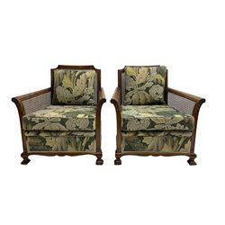 Early 20th century bergère lounge suite, mahogany framed with cane work back and sides, acanthus scroll carved uprights - three seat sofa (W167cm, H82cm, D83cm), and pair matching armchairs (W78cm), loose cushions upholstered in acanthus leaf scroll fabric with scatter cushions