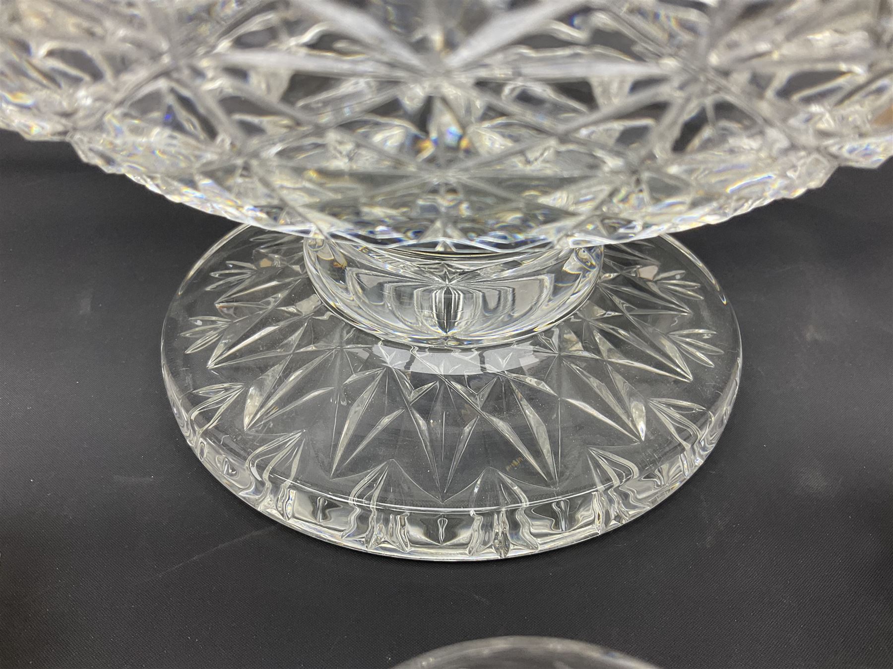 Large Stuart crystal pedestal punch bowl, of circular form, the rim with engraved floral decoration, upon spreading circular foot with radial cut decoration, with seven matching Stuart crystal drinking glasses, each with a C handle, each acid signed beneath, bowl H20cm