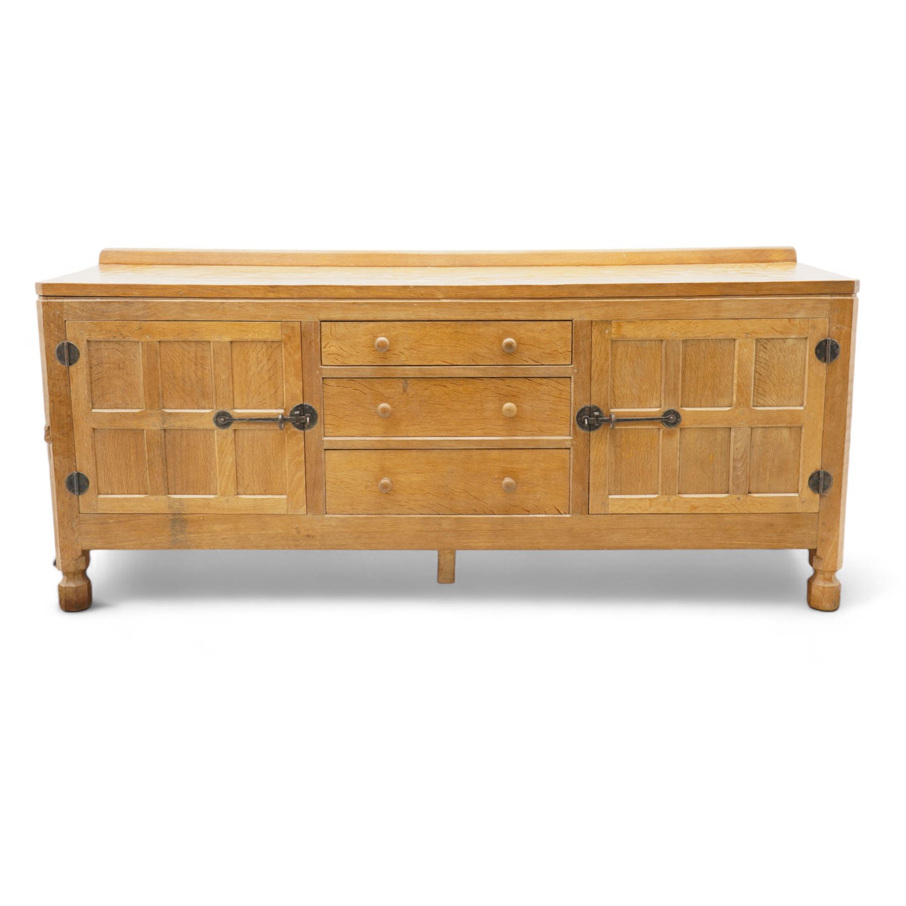 Mouseman - adzed and panelled oak 6' sideboard, fitted with four central drawers and flanking cupboards, enclosed by two panelled doors with wrought metal latches and hinges, on octagonal feet, carved with mouse signature, panelled sides, by the workshop of Robert Thompson, Kilburn 