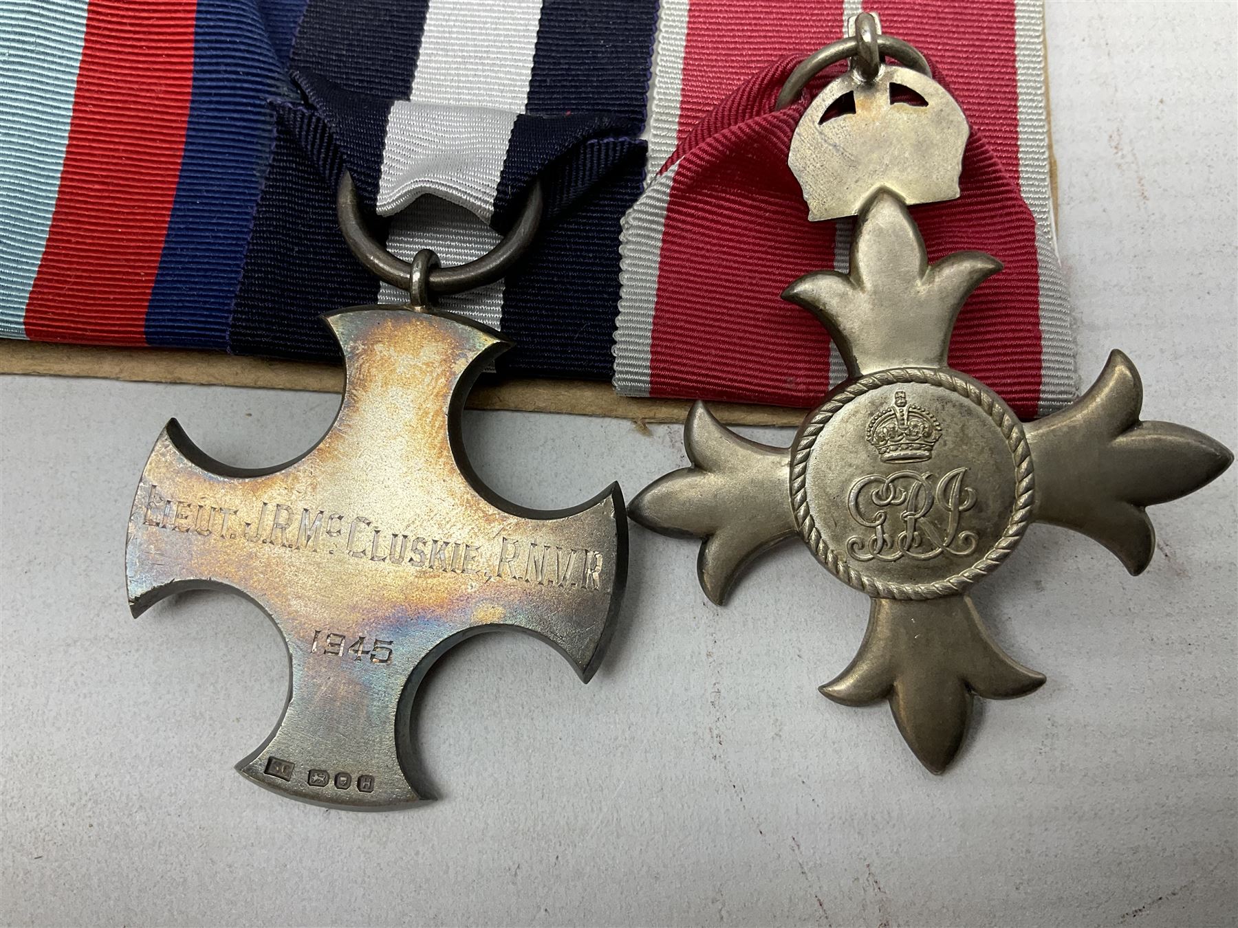 WW2 Royal Naval group of eight medals comprising OBE, hallmarked silver Distinguished Service Cross inscribed verso Lieut. J.R. McCluskie RNVR 1945, 1939-1945 Star, Atlantic Star, Africa Star, 1939-1945 War Medal, Defence Medal and Royal Naval Patrol Service Medal inscribed Lieutenant J.R. McCluskie Royal Naval Patrol Service; with seven original photographs of a sea battle 27th November 1940 against the Italian Fleet and another photographic postcard of Sir Stafford Cripps arriving on board one of the vessels.