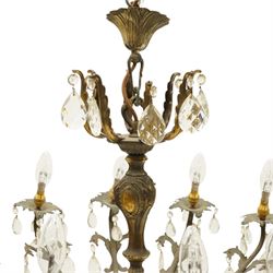 20th century Louis XV design gilt and patinated metal twelve-light chandelier, the foliate-cast baluster stem issuing scrolling acanthus branches with leaf-form drip pans, hung throughout with faceted glass pendants and lustre drops, suspended from chains beneath a foliate ceiling rose