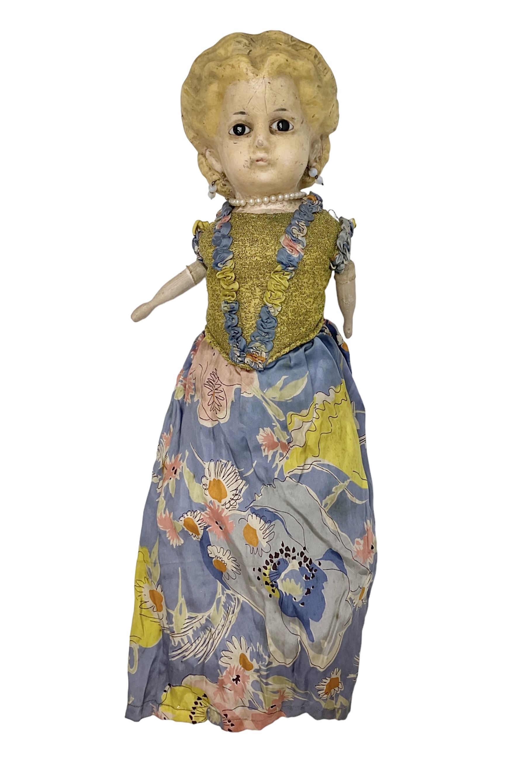 Victorian large wax over composition Pumpkin head doll, with inset dark glass eyes, moulded blonde hair in curls, stuffed body with carved and painted wooden limbs, grey painted boots, floral satin dress with netting underclothes H61cm