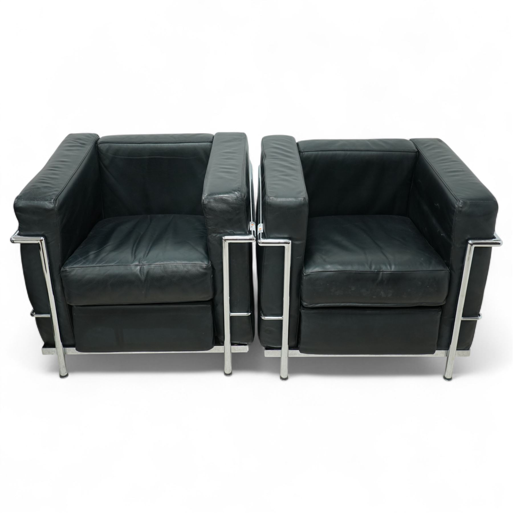 Contemporary pair of black leather chrome arm chairs of Le Corbusier LC2 inspired design, cube form with loose seat and back cushions enclosed in a tubular chrome frame and supports