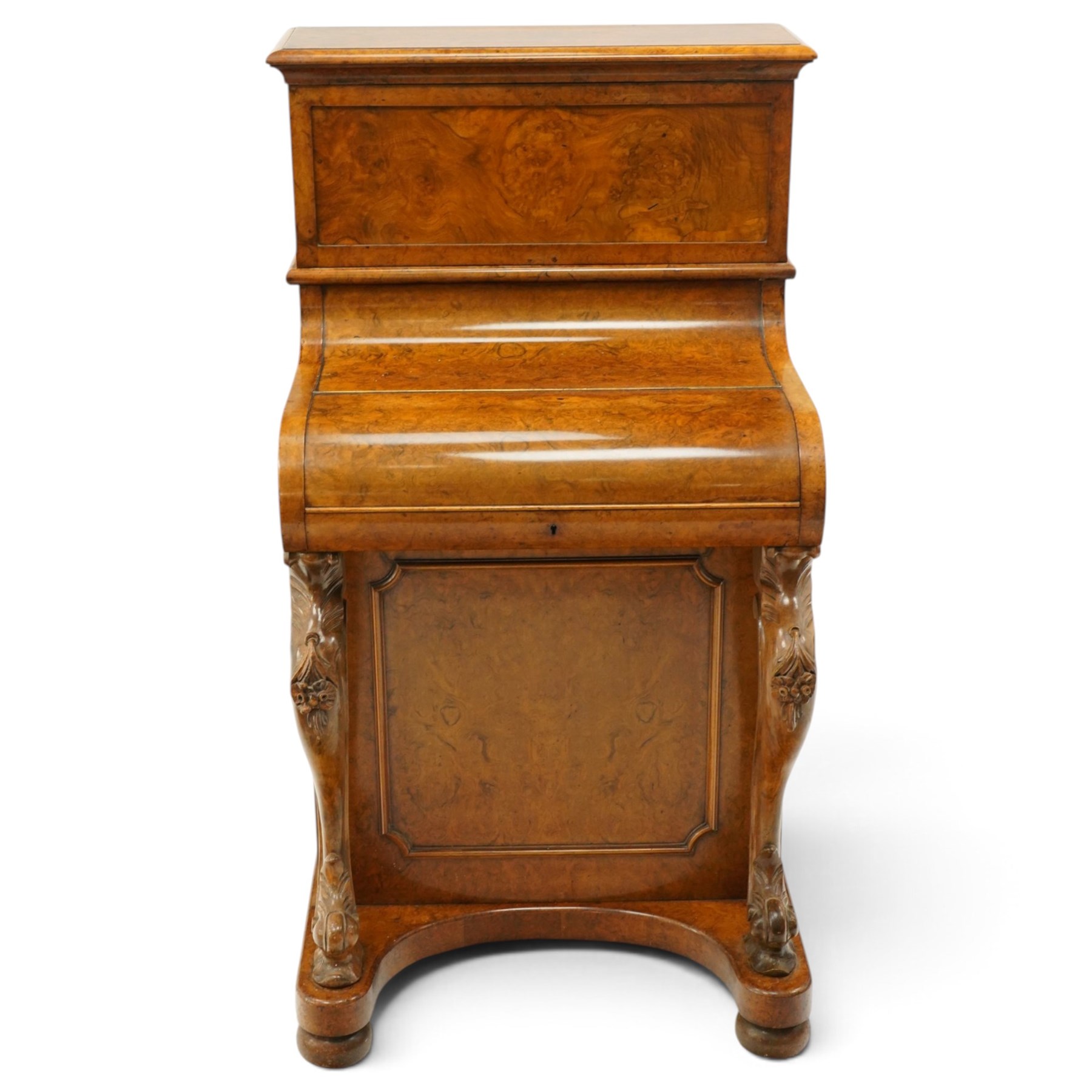 Victorian burr walnut piano-top Davenport, the raised rectangular superstructure with moulded cornice above a panelled fall-front enclosing drawers, the curved hinged writing slope opening to reveal a fitted interior above a sliding tooled leather writing surface, flanked by carved foliate scroll supports, the right side fitted with four drawers behind an arched panelled cupboard door with brass inset campaign-style handles, on a shaped plinth base and bun feet