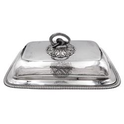 George III silver entree dish and cover, of rounded rectangular form, the base with oblique gadrooned edge, the cover with foliate mounted serpent ring handle, engraved with crest to each side, hallmarked Paul Storr, London 1804, including handle H12cm not including handle H8cm W29.5cm D20.5cm, approximate weight 59.28 ozt (1843.8 grams)