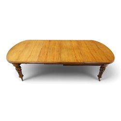Large Victorian oak extending dining table, the rectangular top with rounded corners and moulded edge, plain frieze over large turned lobed and fluted supports terminating to brass cups and castors, with two additional leaves