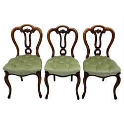 Set of six carved Victorian walnut balloon back dining chairs, button upholstered in green velvet fabric, back with foliate carved decoration supported on scroll form legs 