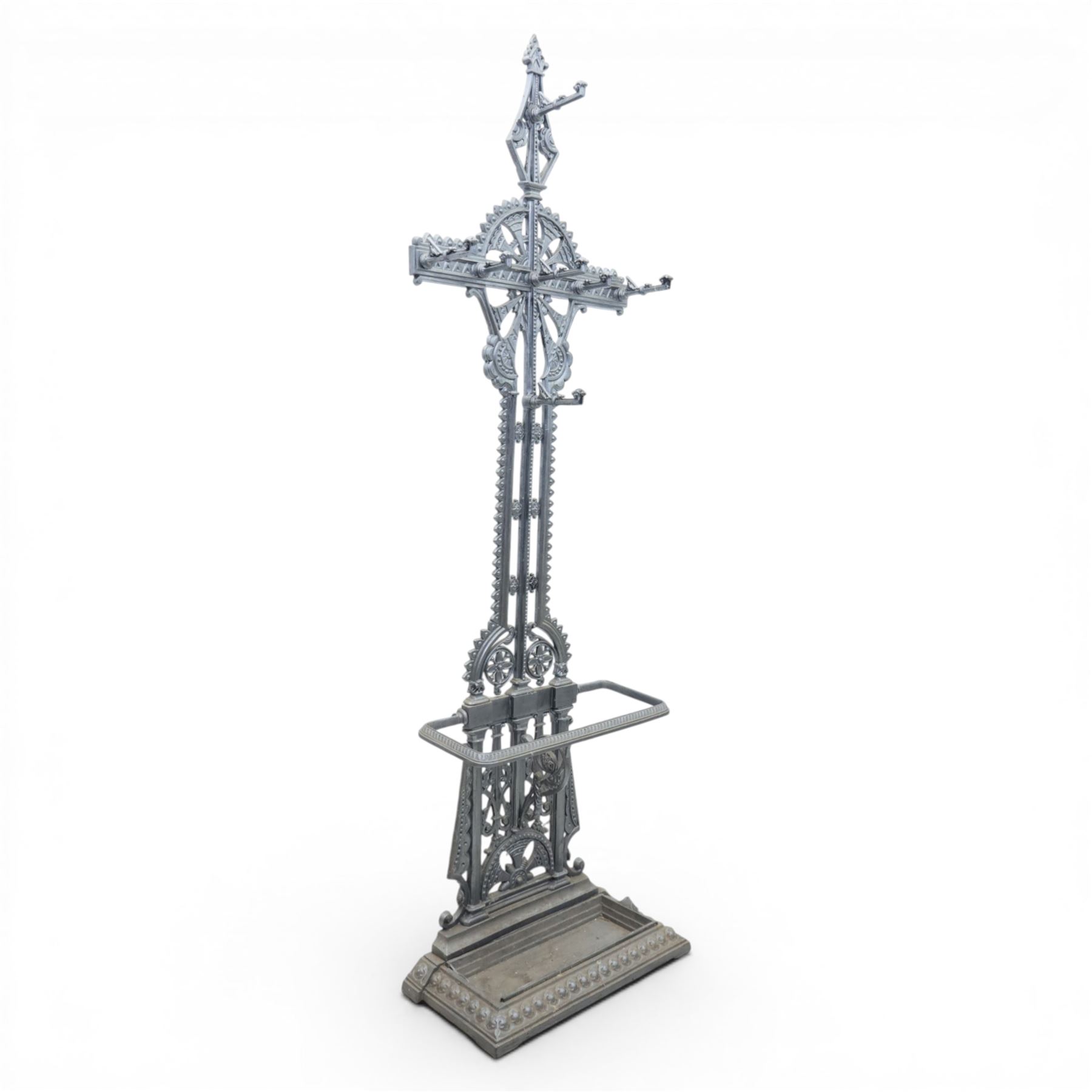 Late 19th century cast iron hall stand in the style of Christopher Dresser, cross shaped upper section with radiating wheel motif and applied hooks, architectural upright with pierced Gothic and geometric detail, fitted with rectangular drip tray and pierced surround, raised on stepped plinth base with bead decoration