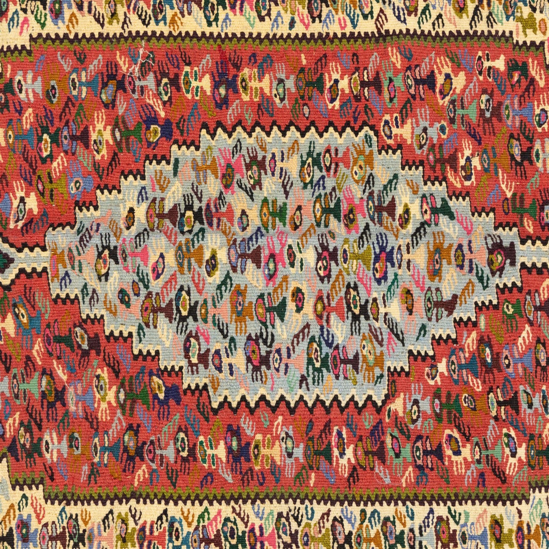 North West Persian Senneh kilim, finely woven wool with elongated central lozenge medallion on a densely patterned field of boteh motifs, in tones of red, ivory, indigo and ochre, framed by floral and diamond guard borders