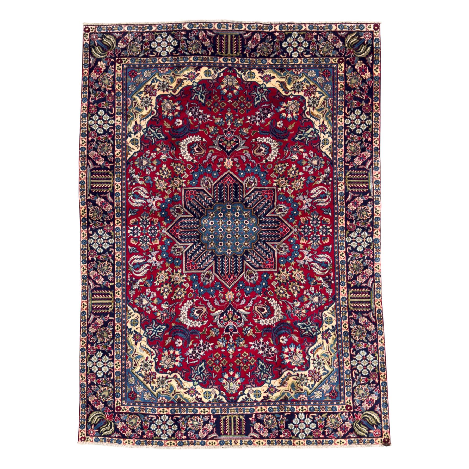 Central Persian Isfahan Carpet, hand-knotted, featuring a bold central rosette medallion on a rich red field, flanked by stylised floral sprays, scrolling foliage and mythical animals, within a broad indigo border decorated with alternating cartouches and flowerheads