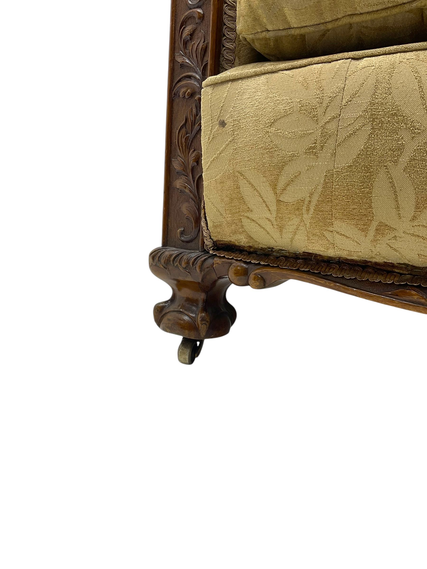 Early 20th century mahogany framed three-piece lounge suite - three-seat camelback sofa (W203cm, D105cm); pair of matching armchairs (W95cm, D96cm); upholstered in neutral foliate pattern fabric, carved with trailing leafy branches, ball and claw carved feet with brass castors 