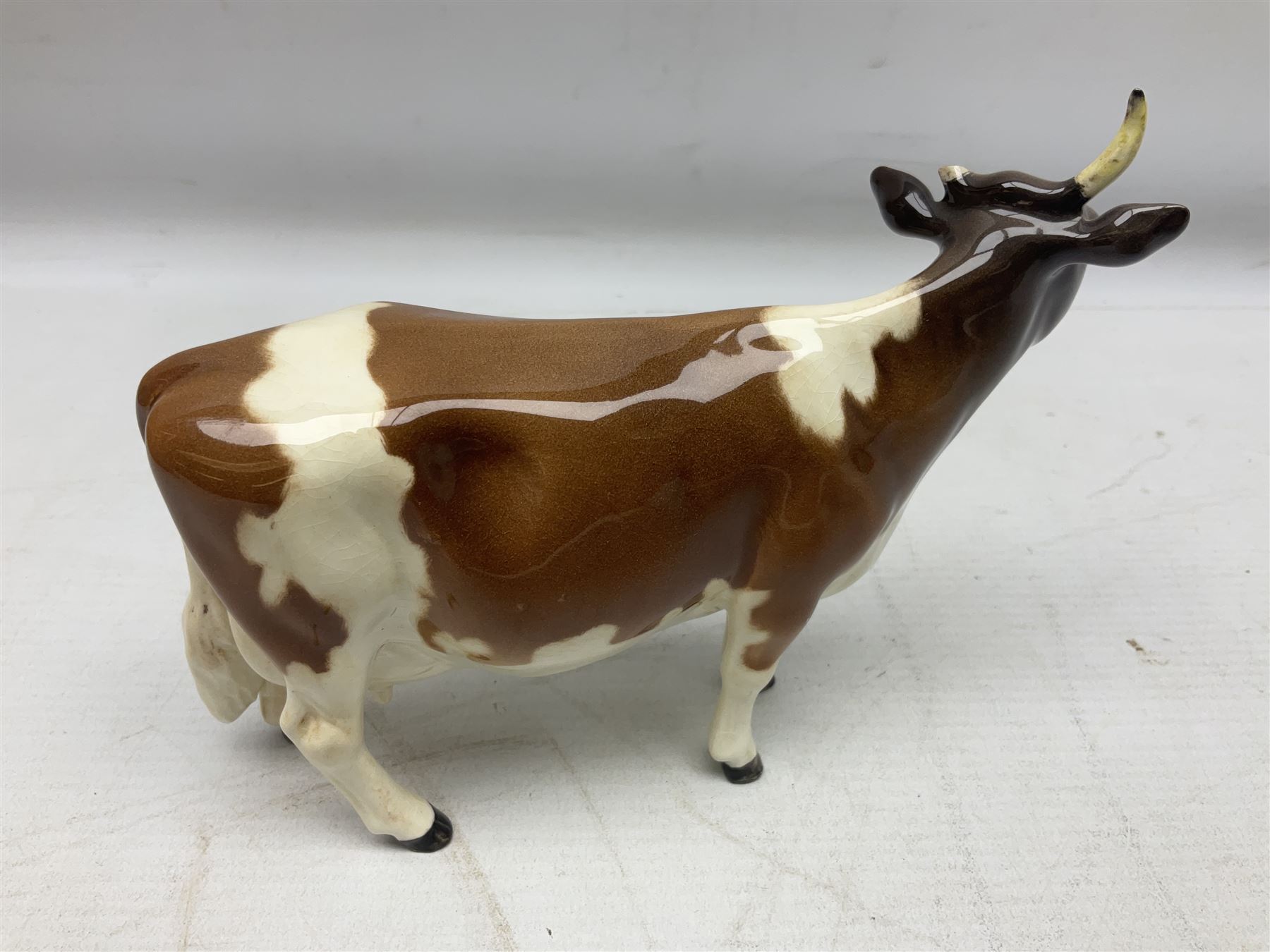 Five Beswick figures of cattle Comprising Ayrshire Bull Ch Whitehill Mandate, no 1454B, three Ayrshire Cow Ch Ickham Bessie, no 1350 and Ayrshire Calf, no 1249B, all with printed marks beneath