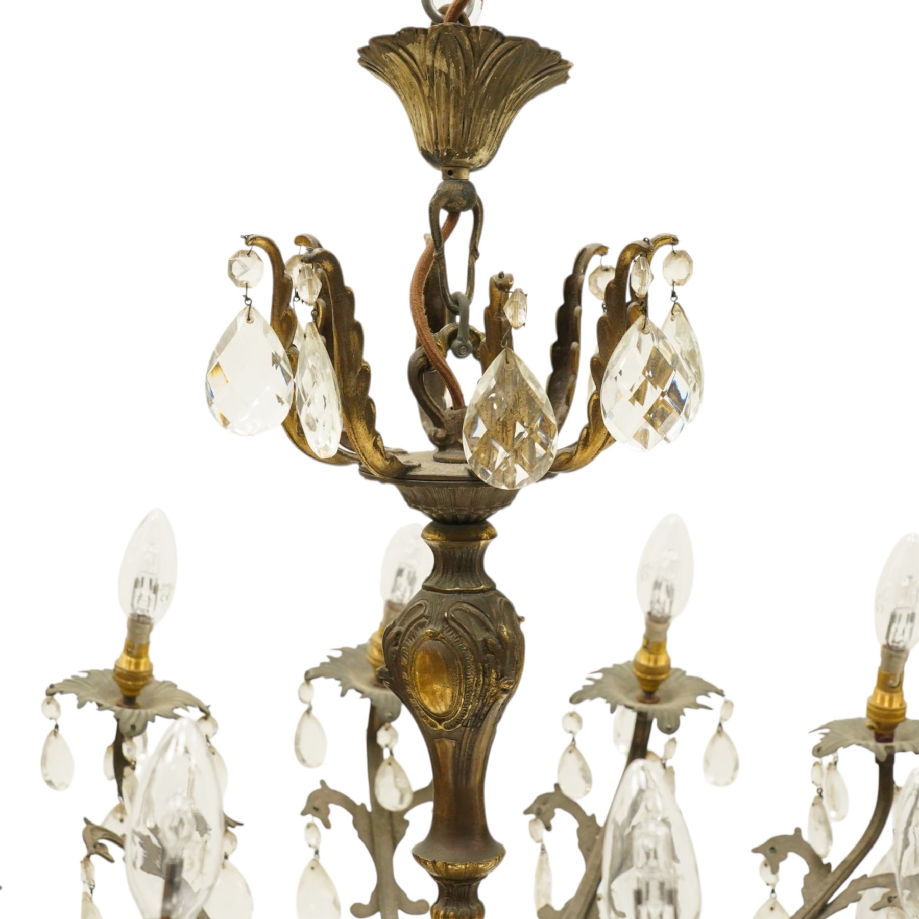 20th century Louis XV design gilt and patinated metal twelve-light chandelier, the foliate-cast baluster stem issuing scrolling acanthus branches with leaf-form drip pans, hung throughout with faceted glass pendants and lustre drops, suspended from chains beneath a foliate ceiling rose