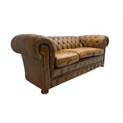 Chesterfield three seat sofa, upholstered in buttoned tan leather with studded detail, on turned feet