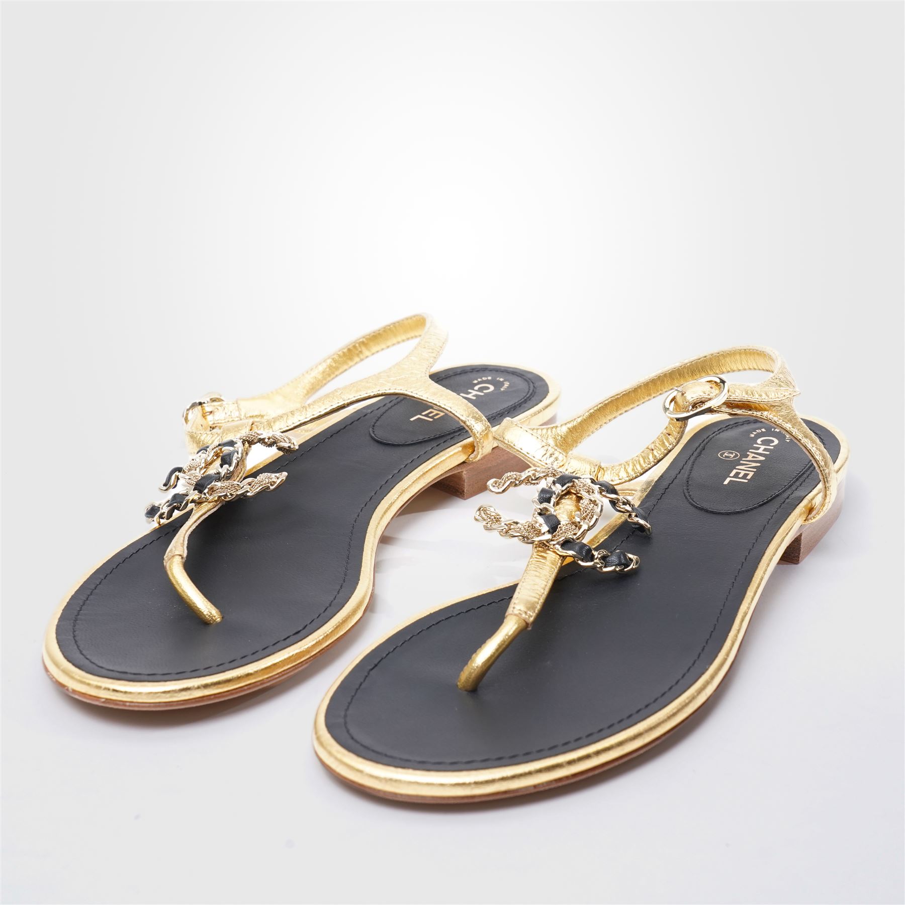 Chanel - pair of gold leather thong sandals, from the 2021 Summer Collection, the uppers centred with an interlocking gold tone CC motif in chain and leather, size 37C, unused with original dust bags