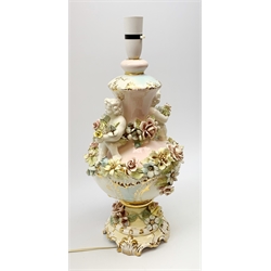 An Italian Capodimonte style lamp base, of pedestal urn form with applied putti and encrusted flower detail, heightened with gilt, overall H46cm. 