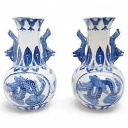 Pair of Chinese blue and white vases and stands, of baluster form with elongated neck, decorated with painted scenes of dragons amongst clouds, the twin handles formed as two crouching dragons, including stands H32cm
