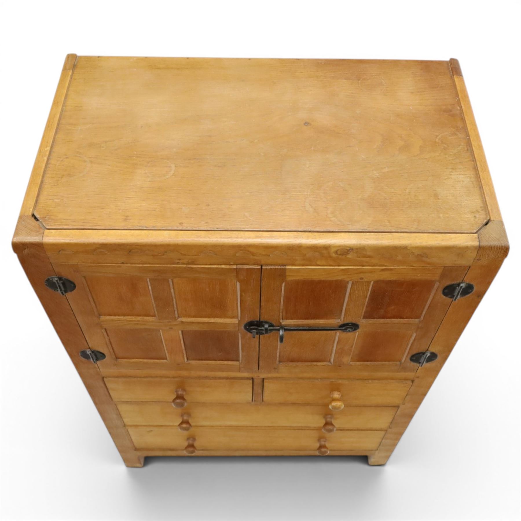 Mouseman - mid-20th century adzed and panelled oak tallboy chest, arcade carved cresting rail over two panelled cupboard doors with wrought iron fittings and latch, enclosing single shelf, over two short and two long drawers with lightly adzed facias and turned knob handles, raised on square supports, relief carved mouse signature, by the workshop of Robert Thompson of Kilburn