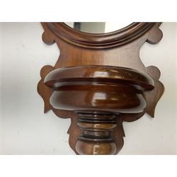 Mahogany wall bracket with circular mirror plate set against a shaped mahogany back with turned detail beneath a semi-circular well, H76cm