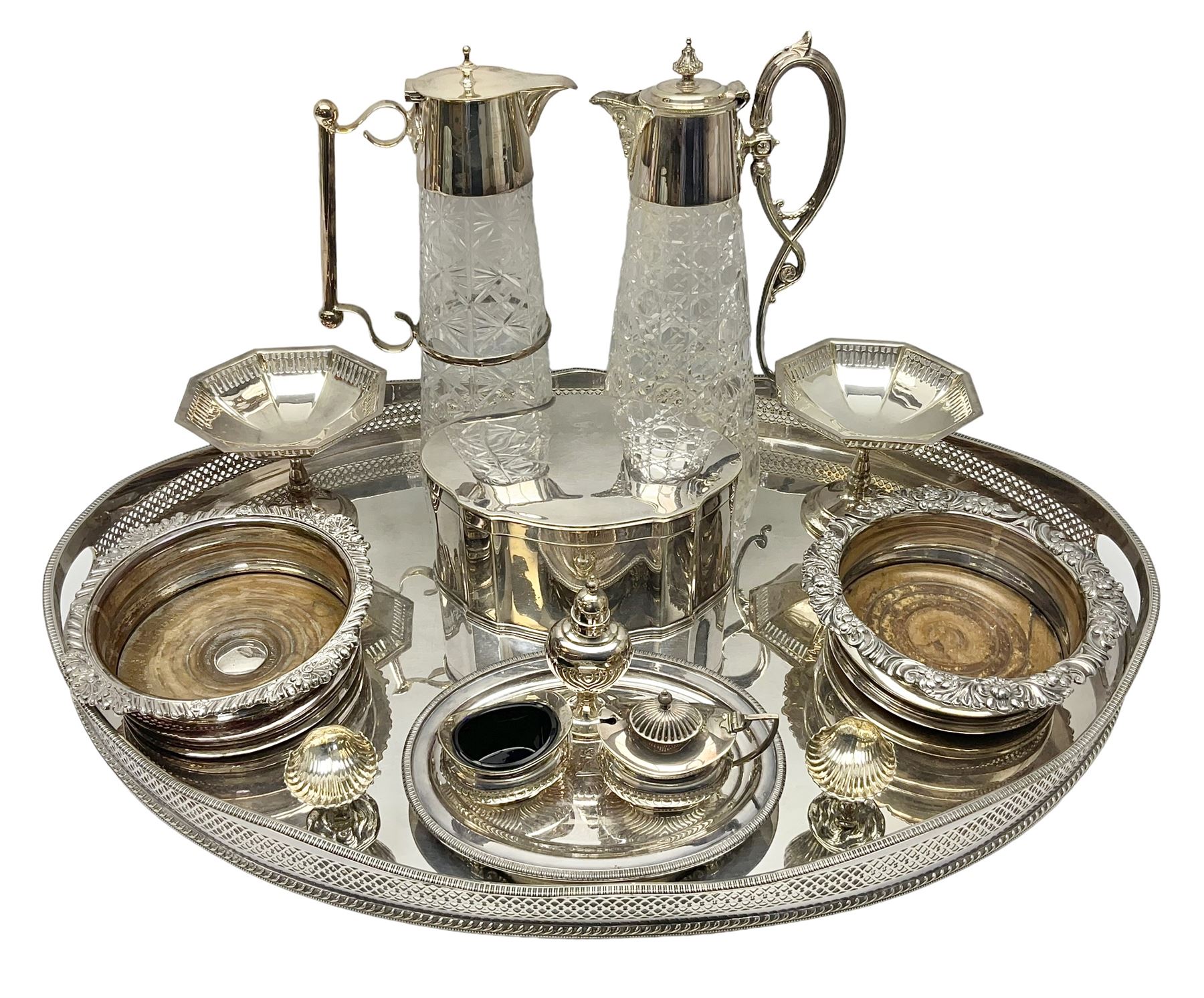 Pair of Mappin and Webb silver plate pierced pedestal bon bon dishes, together with other silver plate comprising teapot stand engraved with lion's head to centre, two cut glass claret jugs, two bottle coasters with acorn decoration, two open salts upon dolphin mounts, tea caddy, three piece cruet set and a large oval tray with pierced sides and upon four ball feet