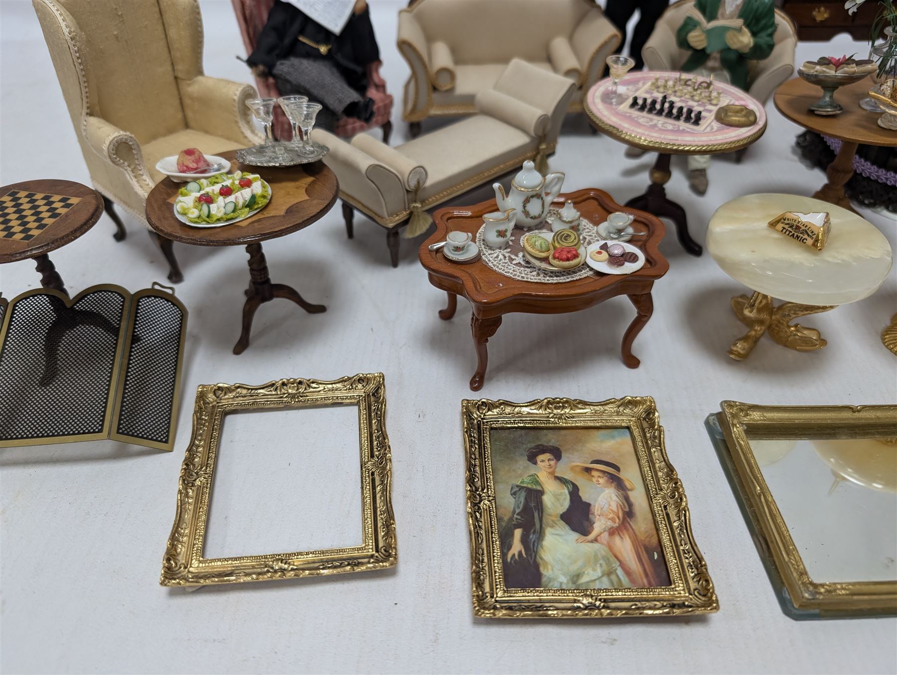Dolls house furniture, including sofa, chairs, foot stools, fireplace, sideboards, five figures, mirrors, paintings and accessories