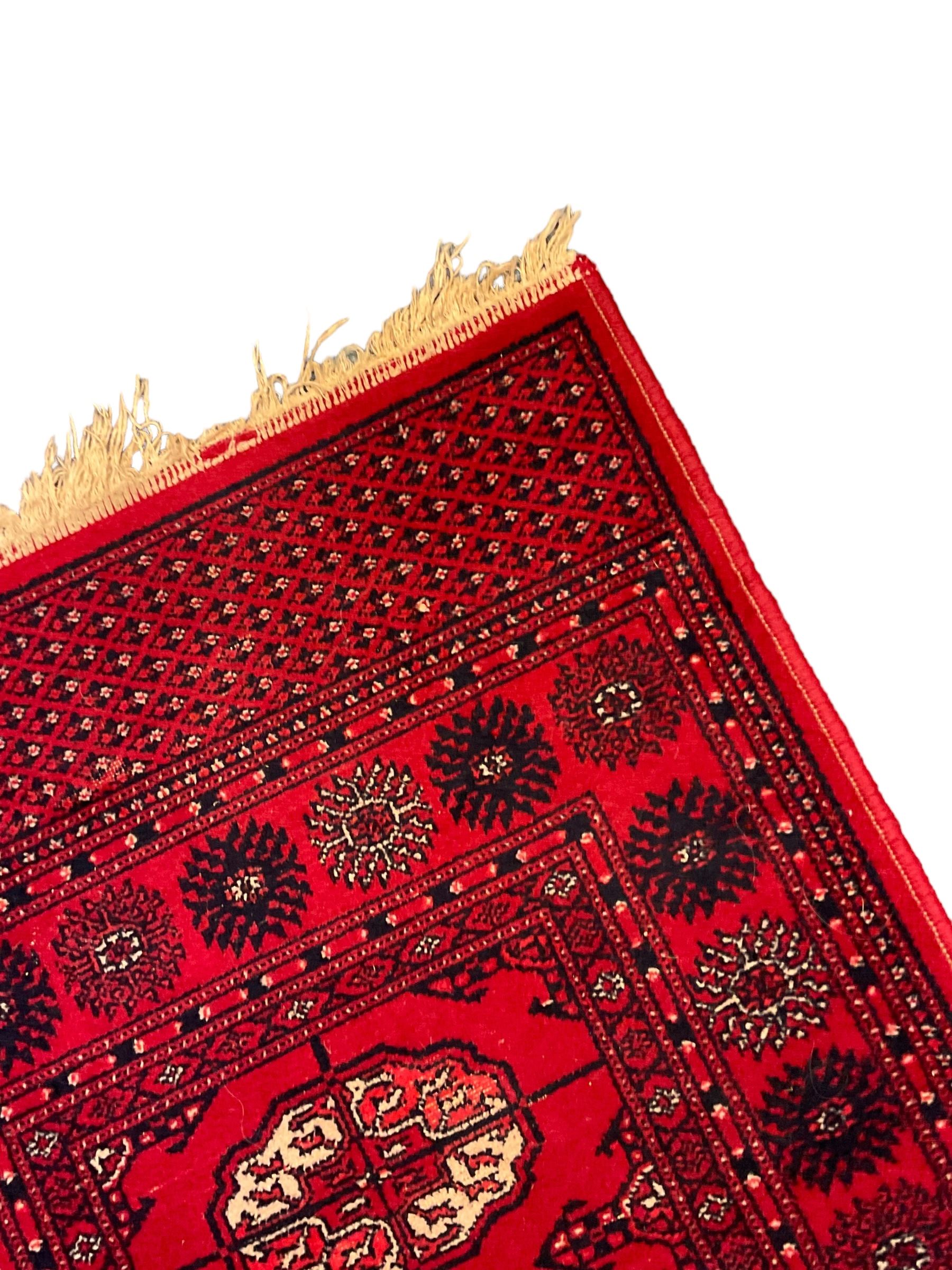 Persian design red ground runner, the field decorated with repeating Boteh motifs, five-band border (277cm x 74cm); Bokhara design red ground rug, decorated with a single row of Gul motifs (272cm x 69cm)