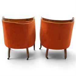 Pair of Edwardian inlaid mahogany tub armchairs, traditional shape with satinwood stringing, upholstered in crimson fabric with sprung seat, on square tapering supports with castors