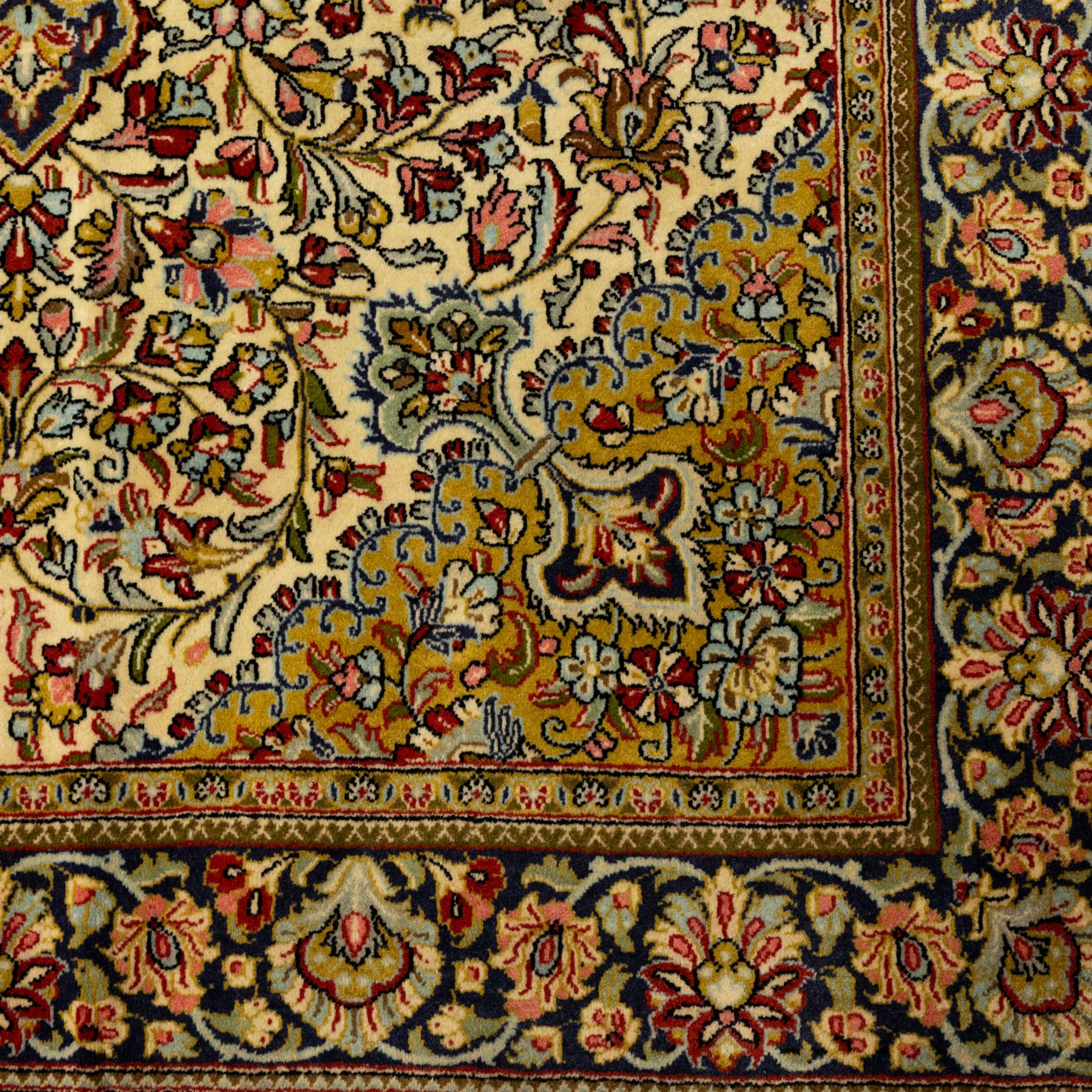 Fine Qom hand-knotted rug, ivory ground, with a dark navy shaped floral medallion and pendants, the field densely worked with fine flowering vines, palmettes and leafy scrolls in red, green, ochre and blue tones, within golden spandrels and a dark navy floral border, flanked by narrow guard stripes, with cotton fringes
