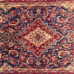 North West Persian hand-knotted Sarouk rug, central navy ground field with cusped lozenge medallion with pendant motifs, scrolling palmettes, and floral sprays, cream spandrels, and madder red border of stylized rosettes and leafy meandering vines between multiple guard stripes 