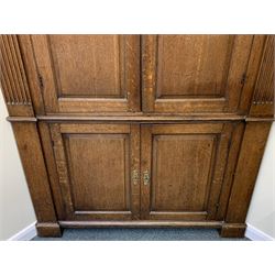Large George III oak corner cupboard, projecting cornice over two stepped arch doors with fielded panels and blind fret work spandrels, flanked by fluted uprights, cupboard below enclosed by two fielded panel doors, the painted interior fitted with shaped shelves
 