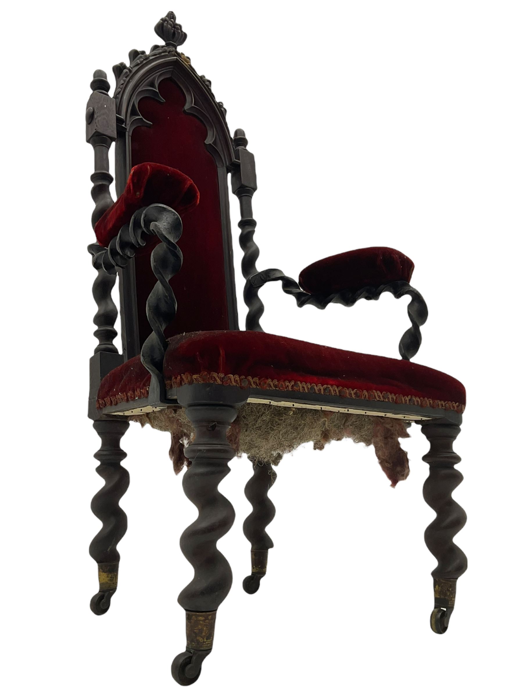 Victorian oak and wrought metal Gothic open armchair, the pointed arched back carved with foliate, cusped inner arch upholstered in red, spiral turned uprights and supports, with arms made of spiral forged metal