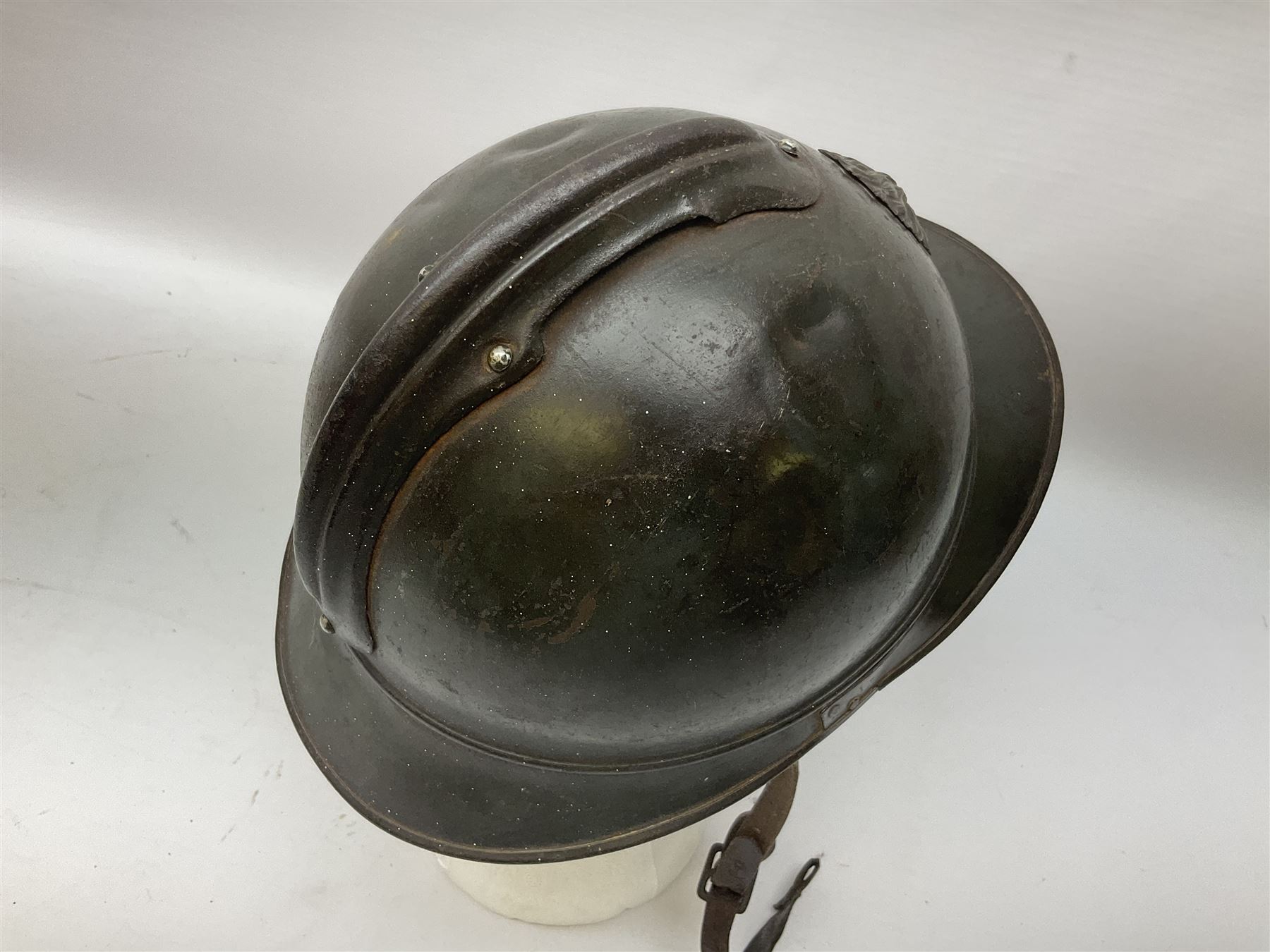 WW2 French M-26 Adrian Pattern Steel Helmet, original olive drab paint finish; flaming grenade badge to the front signifying issue to an Infantry regiment; original leather liner and leather chinstrap; and WW2 Dutch steel helmet with liner and chin strap (2)