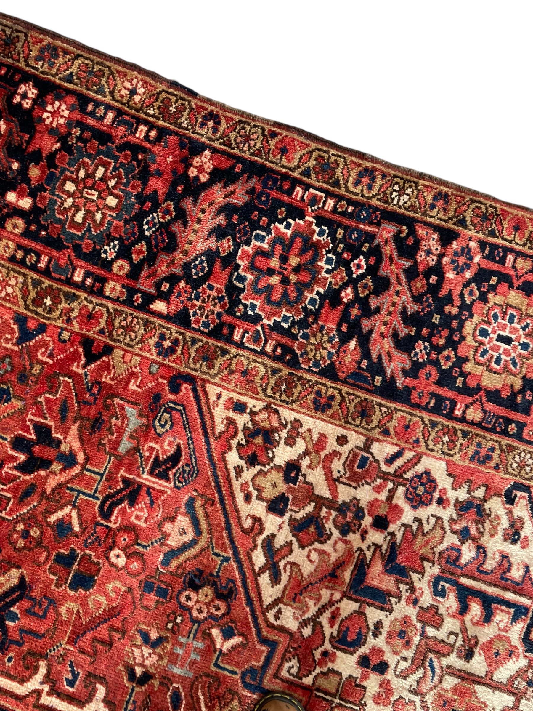 Persian Heriz red ground carpet, large stylised pole medallion surrounded by Pitrak motifs, indigo ground border decorated with stylised flower heads and trailing leafy branches, within floral pattern guard stripes