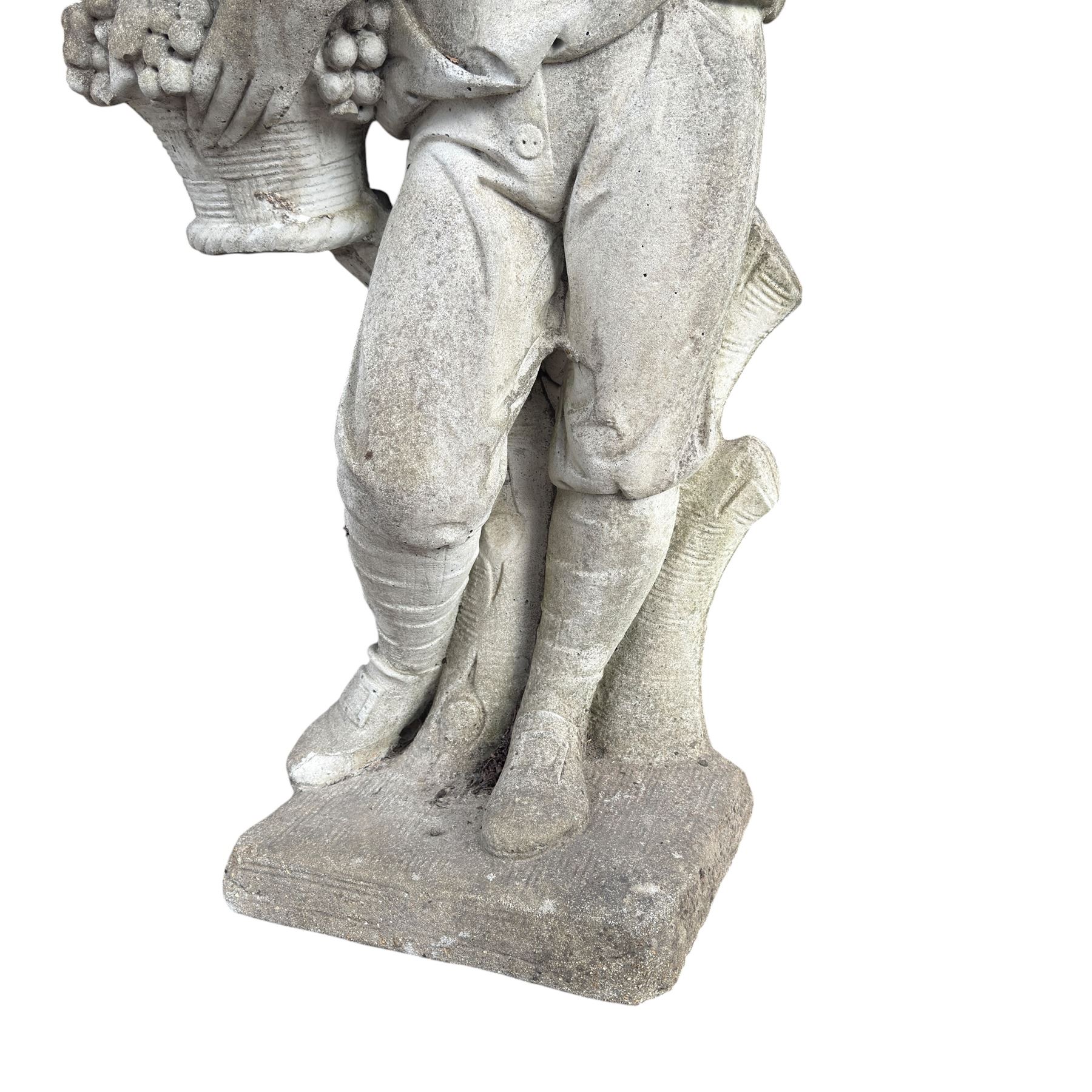 Haddonstone - weathered cast stone garden statue of a boy holding a basket of grapes, modelled with curled locks of hair wearing a tunic and breeches leaning against a naturalistic tree stump, on square base