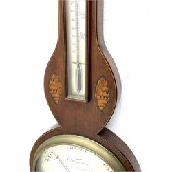 Early 19th century William IV mercury wheel barometer with a rosette inlaid broken pediment and correspondingly inlaid round base, mahogany veneered case with inlaid oval conch shell paterae and satinwood stringing to the edge, with an arched thermometer box and spirit thermometer measuring degrees Fahrenheit from 20 to 120, eight-inch silvered register reading barometric pressure in inches from 28  to 31, with predictions in Roman upper and lower case and script, dial inscribed “A Tagliabue,24 Grenville Street, Luther Lane, London”, with a steel indicating hand, brass recording hand and cast brass bezel.