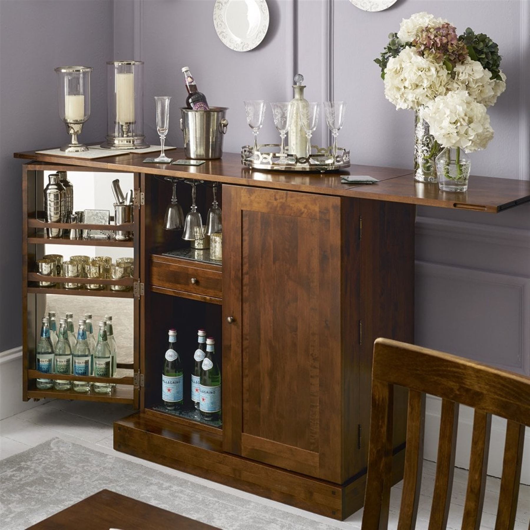 Laura Ashley - contemporary 'Garret' birch and dark chestnut finish bar cabinet, rectangular top with fold-out sides, double front doors enclosing shelving, wine racks, and glass storage, built-in stemware racks and bottle compartments, raised on plinth base
