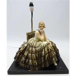  Guido Cacciapuoti (Italian 1892-1953): large ceramic model of a seated lady wearing crinoline dress with rose stems in her hand, mounted on rectangular ebonised plinth, later converted to table lamp, signed verso with original label, L37cm x H32cm excluding fitting   