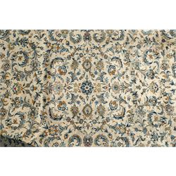 Central Persian Kashan hand-knotted carpet, ivory field profusely decorated with an all-over scrolling vine, palmette, and lotus design in shades of soft blue, pale gold, and green within floral borders