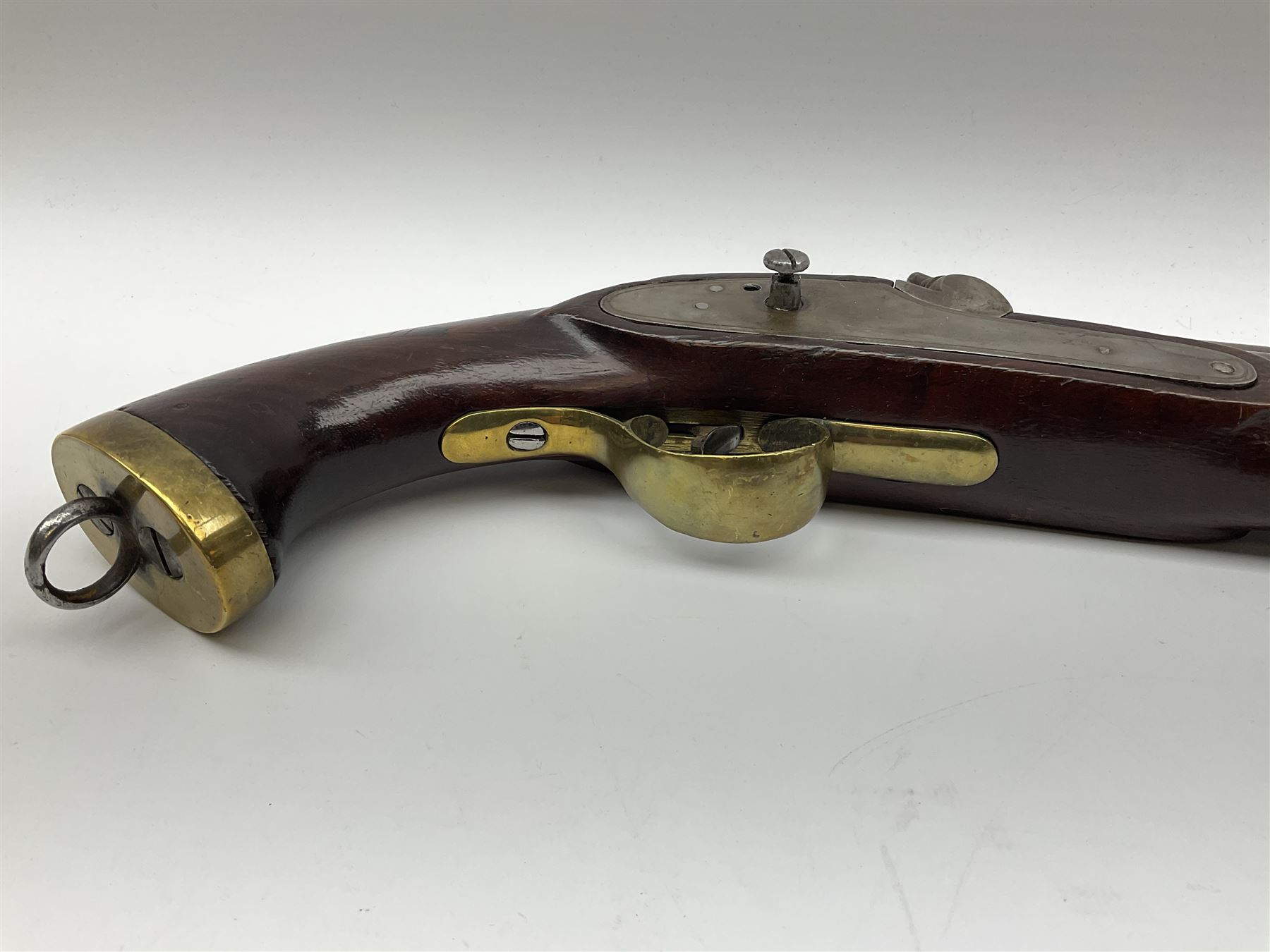Early 19th century percussion cap cavalry pistol with round 23cm unsighted barrel, borderline engraved action lock (lacking hammer), walnut full stock with heavy brass furniture, iron lanyard ring to the flat butt cap and long flat retaining spring below fore-end for captive ramrod (missing) L41cm overall