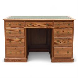 Contemporary stripped and waxed pine pedestal kneehole desk, rectangular top inset with green leather writing surface with brass studded edge, fitted with nine drawers with brass knob handles, above a plinth base on recessed castors