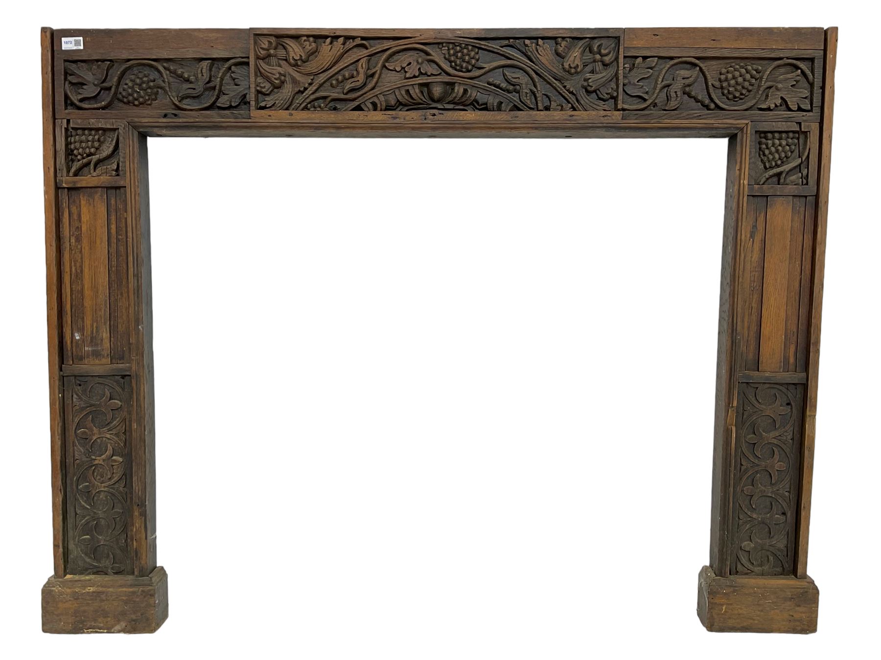 19th century Jacobean Revival oak fire surround, decorated with applied carved panels depicting foliate patterns and stylised grape vines, uprights carved with fleur-de-lis decoration
