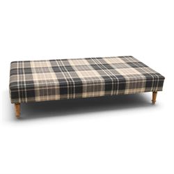 Large traditional design upholstered footstool, upholstered in checked fabric, with loose cushion, raised on a light turned supports 