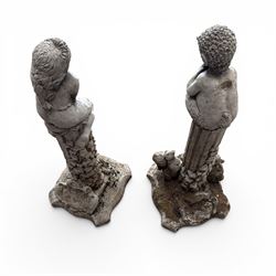 Pair of weathered composite stone garden figures, modelled as a girl and a young satyr playing the panpipes seated on column supports, the fluted columns with climbing ivy vines and surmounted animal, butterfly and other zoomorphic motifs