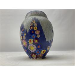 1930s Carlton Ware Art Deco Garden pattern vase of shouldered ovoid form, decorated with blue, pink and yellow flower heads on a mottled blue and white ground, pattern no. 3413, with printed and painted marks beneath, H19cm, together with a Clarice Cliff My Garden pattern vase, raised upon three feet with blue, pink and purple moulded Hollyhock design, H20cm, with Clarice Cliff Wilkinson Ltd England marks beneath