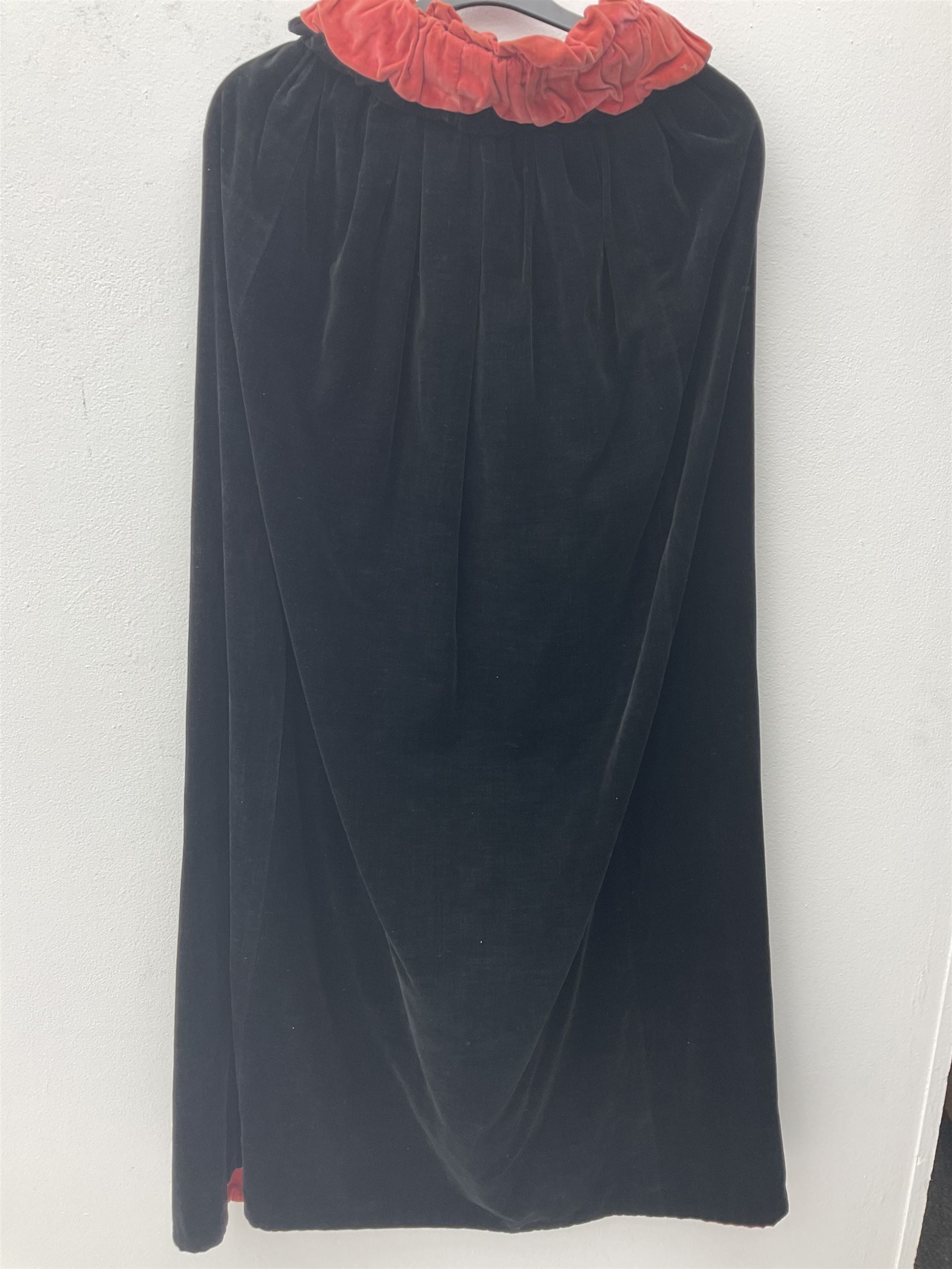Full length 1930's childs black velvet cape, with ruched collar and red velvet lining, with a single button neck fastening 