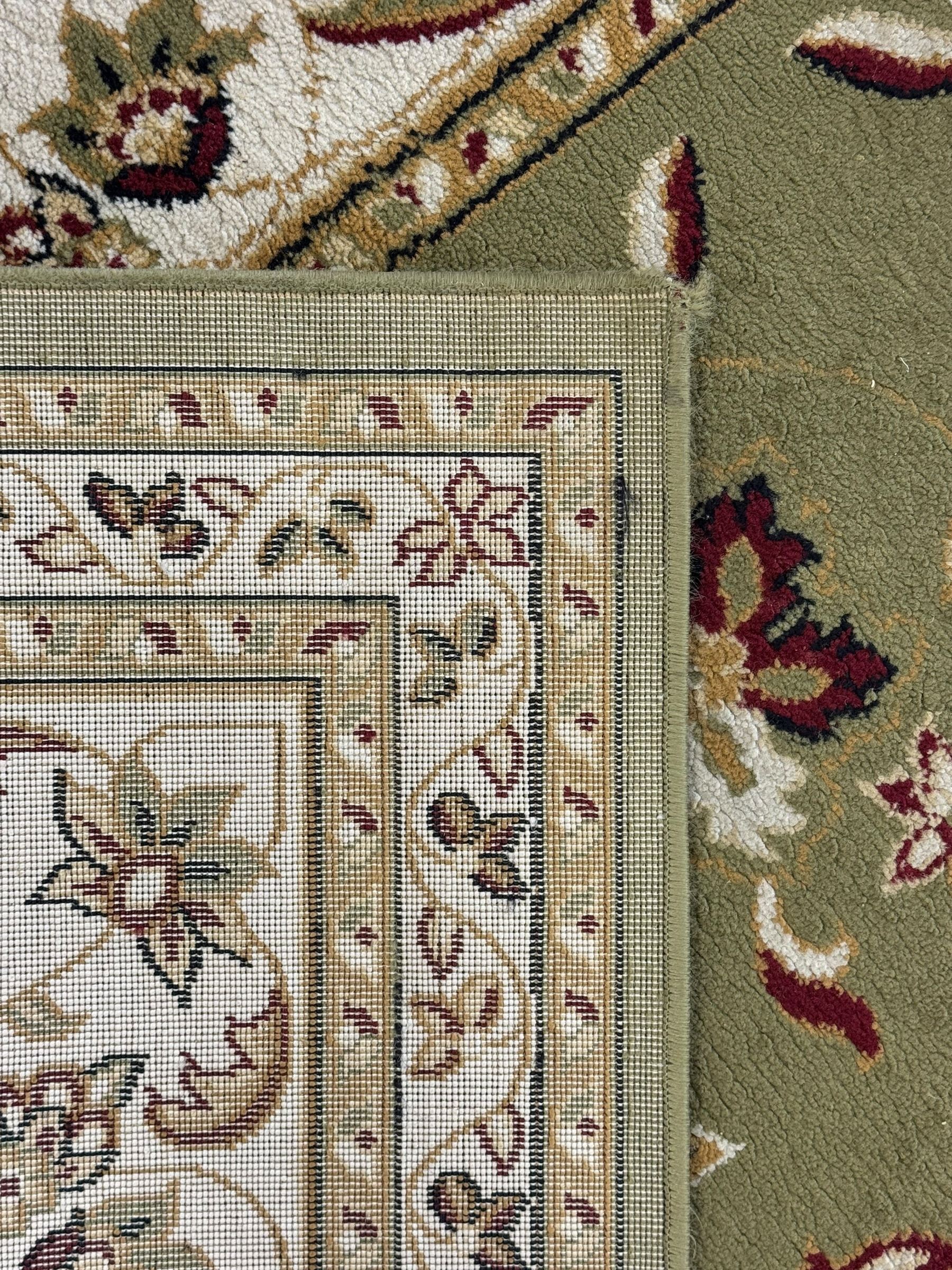 Turkish Sincerity Royale green ground rug, the field decorated with a central floral medallion surrounded by scrolling floral motifs in shades of cream, beige, and burgundy, spandrels filled with matching floral designs, the border featuring a series of floral patterns on a cream ground, finished with green edges