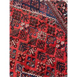 Persian Joshaghan crimson ground rug, stepped lozenge medallion surrounded by repeating foliate lozenge motifs, the border decorated with stylised plant motifs, within geometric guard stripes