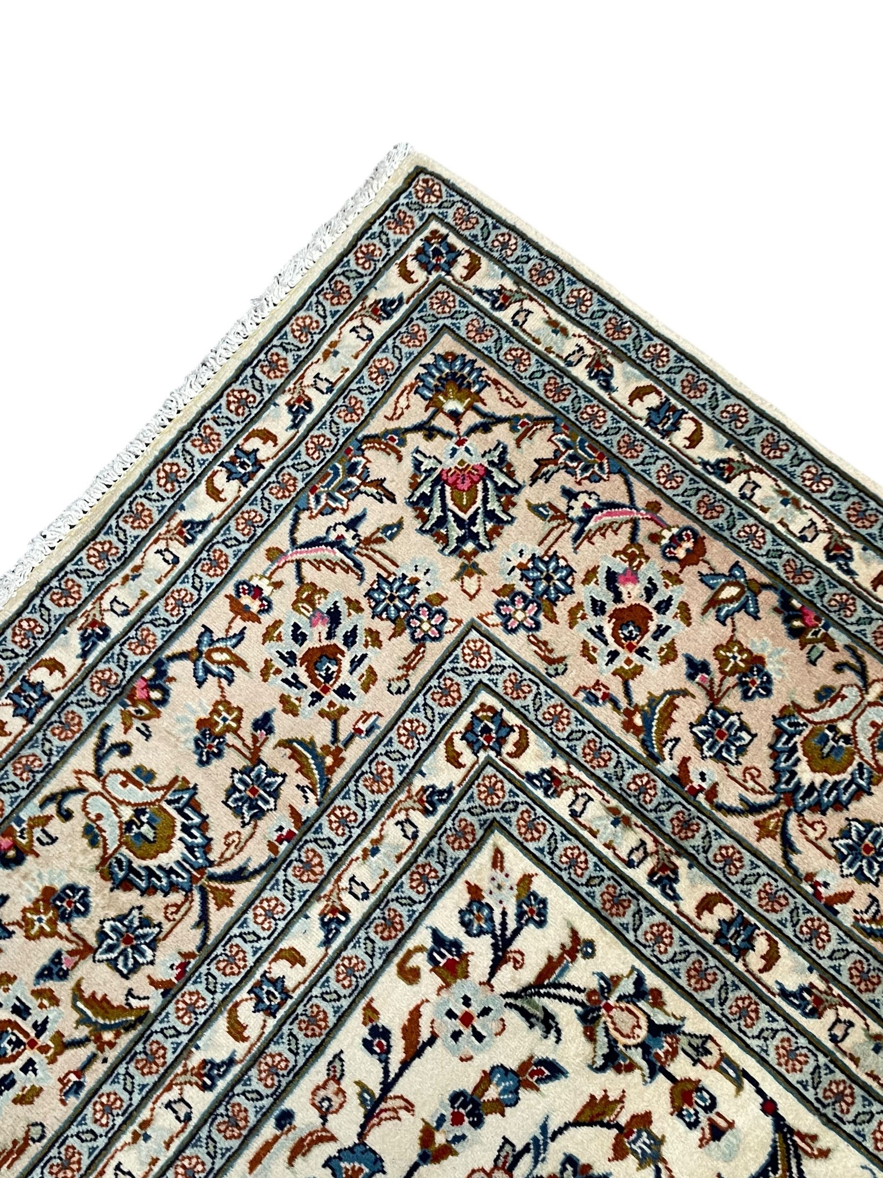 Persian Kashan ivory ground rug, decorated with curled leafy branches and palmettes, the border with scrolling design decorated with further palmettes, within floral pattern guard stripes